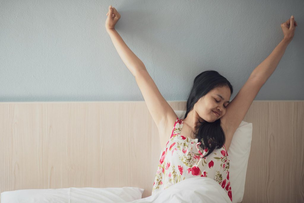 Man stretching in bed during a bright morning after a good sleep