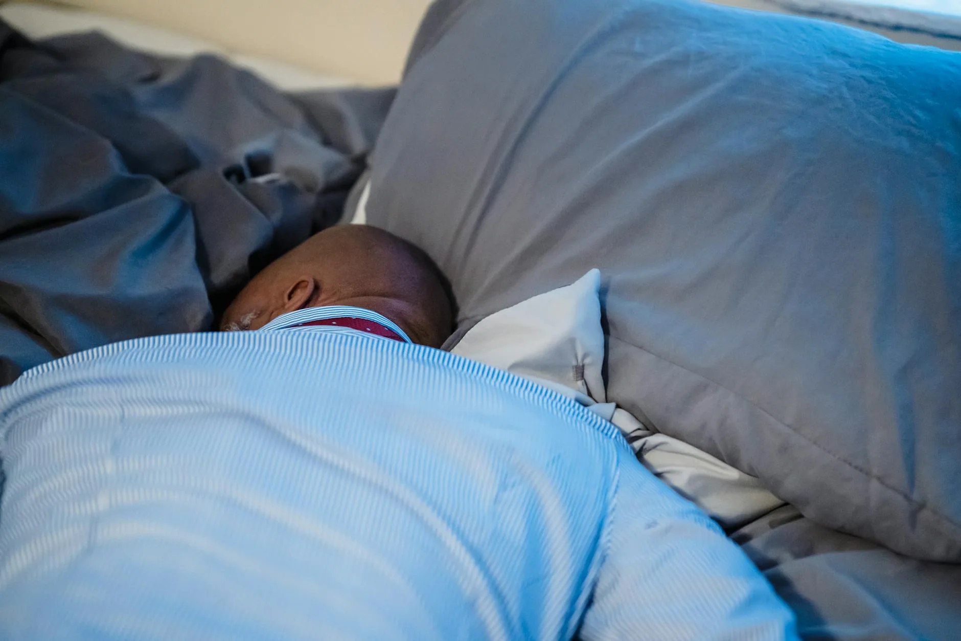 Person sleeping peacefully under a duvet on a comfortable bed