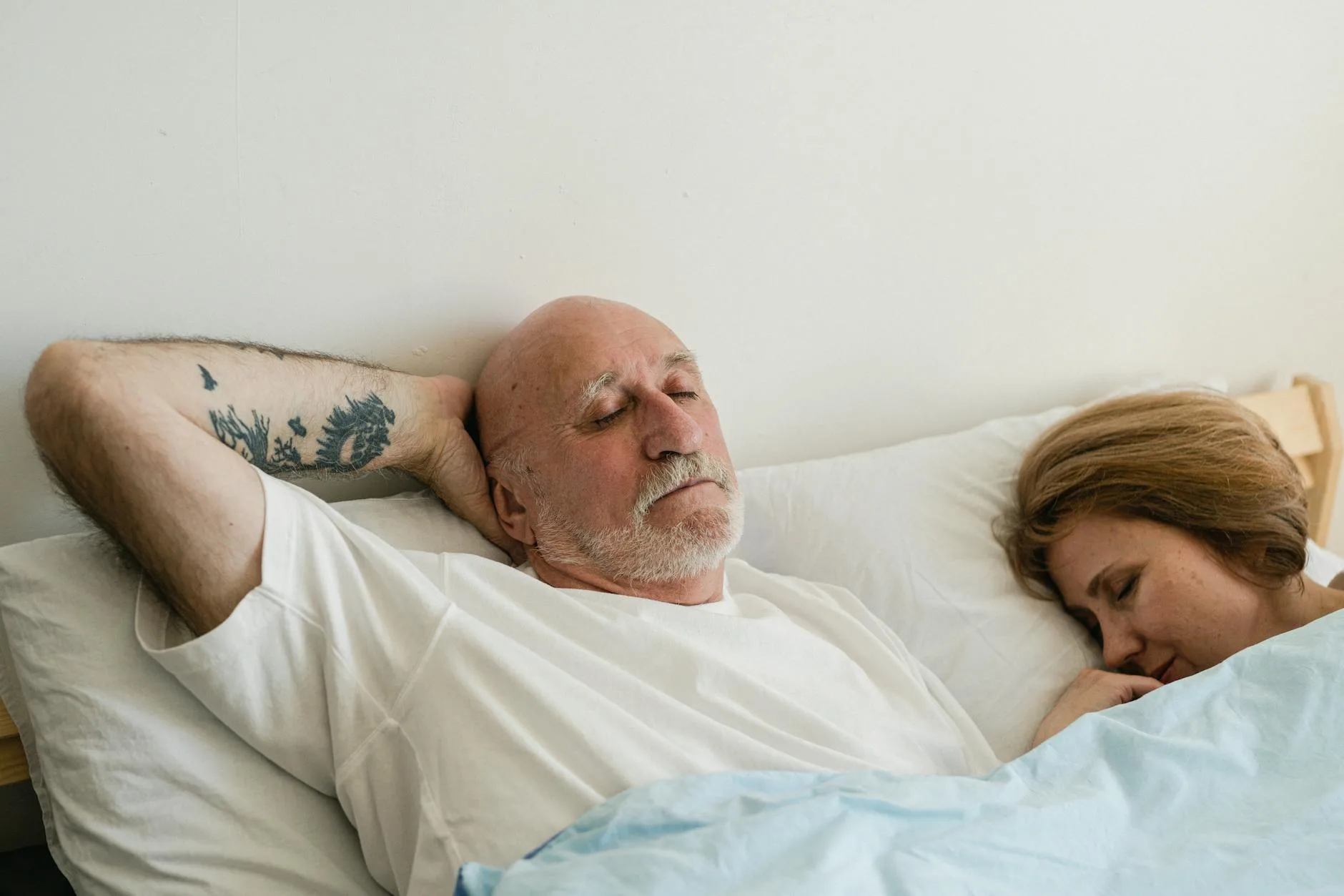 Couple sleeping comfortably on a supportive mattress with white sheets