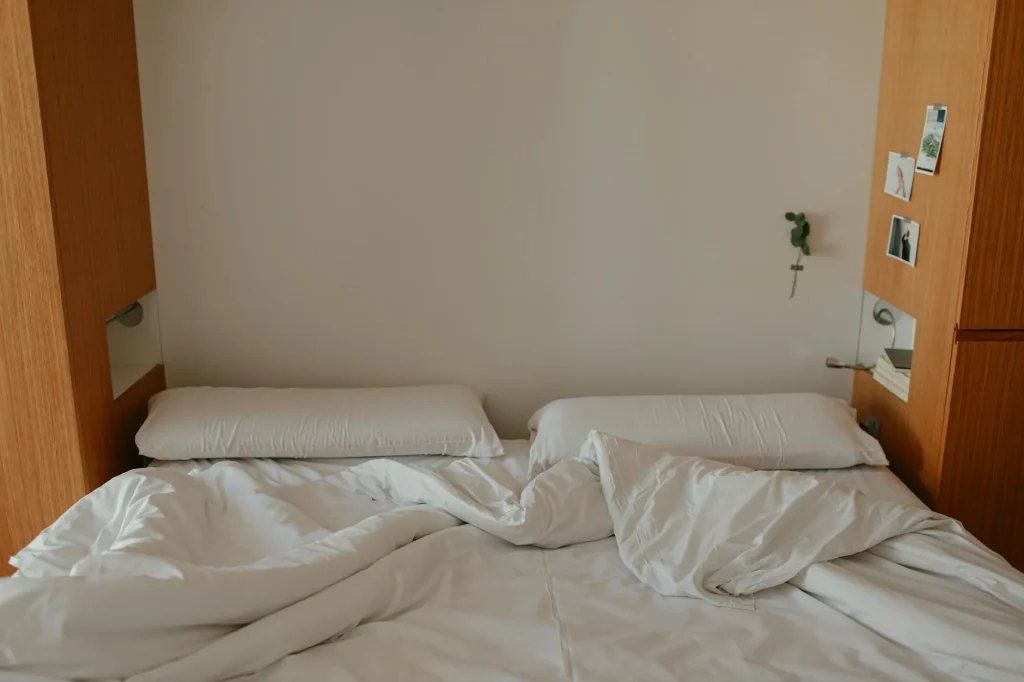 Neatly made bed with white bedding and pillows in a bright bedroom