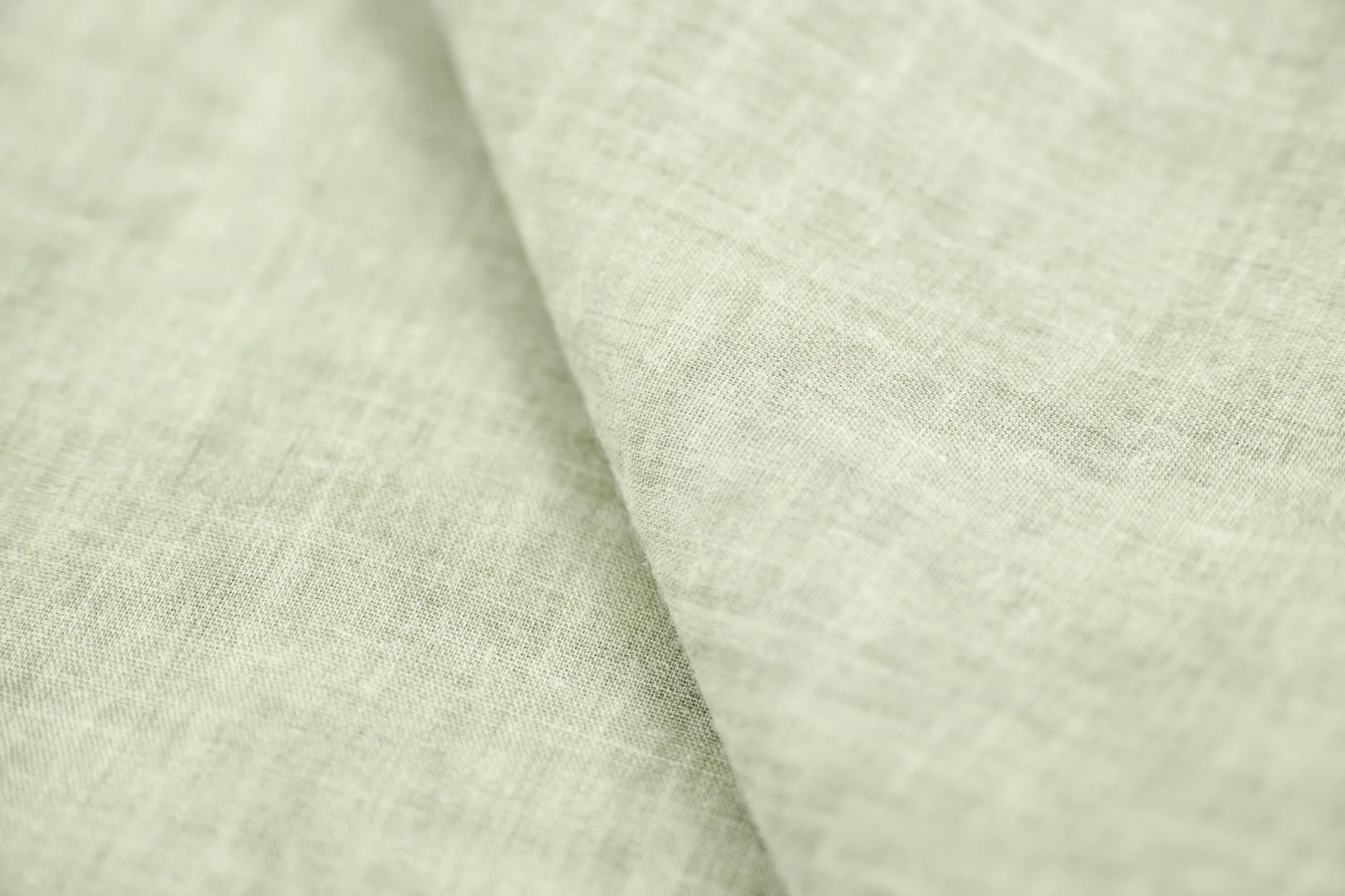 Stack of folded linen bed sheets in neutral tones