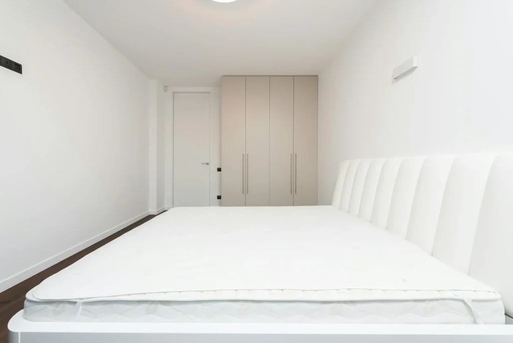 Memory foam mattress on bed frame in clean modern bedroom