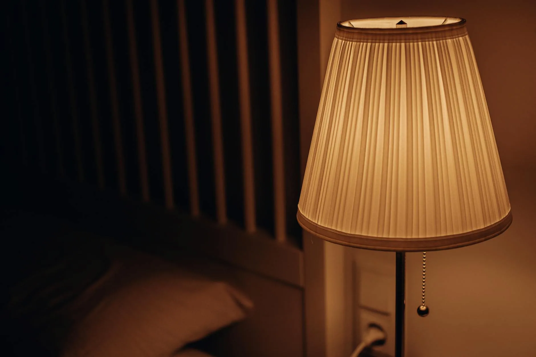 Warm bedside lamp casting soft light in a bedroom at evening